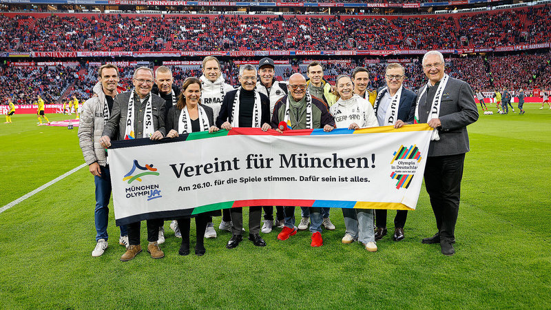 Samstag, 18. Oktober 2025; Beim Bundesligaspiel FC Bayern München gegen Borussia Dortmund versammeln sich Vertreter des FC Bayern, darunter auch Innenminister Joachim Herrmann, sowie Olympiateilnehmende, um die Unterstützung für die Olympischen und Paralympischen Spiele in München zu bekräftigen.